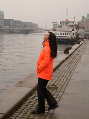 Obraz premium Woman in bright jacket near the canal on a foggy day