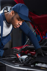 Fototapeta premium african american foreman with screwdriver making diagnostics of car engine.
