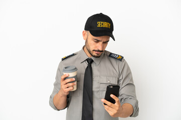 Young security  caucasian man isolated on white background holding coffee to take away and a mobile
