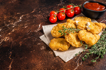 Pile of crispy homemade baked chicken nuggets with ketchup. Dark background. Top view. Copy space