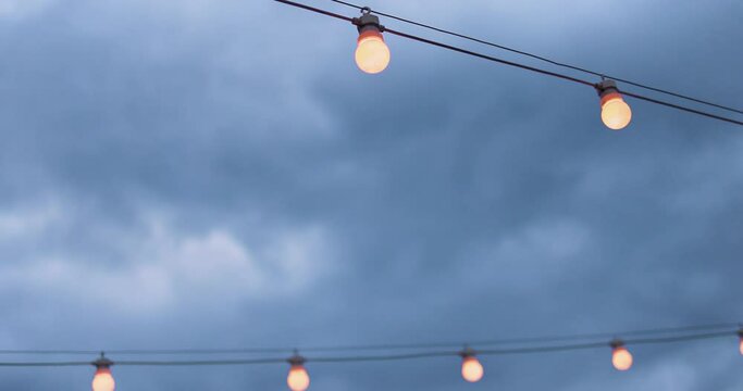 the rows of party light bulb strings over the cloudy sky background