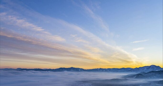 Time lapse of colorful clouds moving over alpine valley in Slovenia. Amazing sunset in winter. Aerial timelapse of inversion clouds rolling in large basin. Static shot