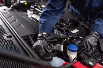 Fototapeta cropped view of mechanic in work gloves fixing engine of car. obraz