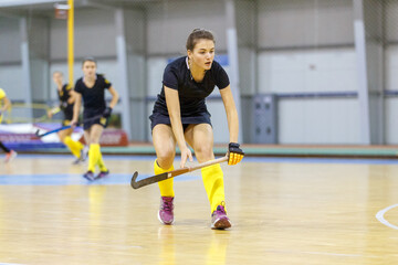 Obraz premium Young hockey player girl in defence against attack in indoor hockey game.