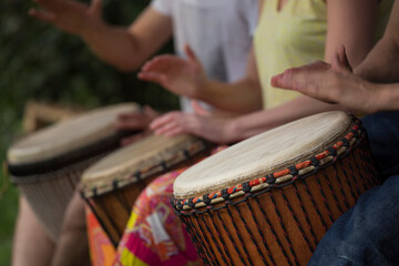 Group of people playing at djembe drums outdoor