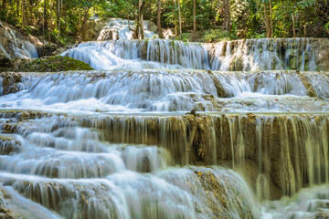 Waterfall cascade close-up at Erawan National Park in Thailand, a popular tourist destination and famous for its emerald blue water. Deep forest in tropical climate with fantasy atmosphere. 
