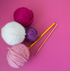 colorful wool balls on pink ground with crochet hooks