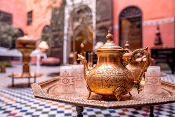 Fes, Morocco. October 10, 2021. Traditional ornate copper teapot with glasses on table