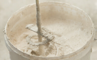 the process of mixing plaster mortar putty mixer in a bucket close-up