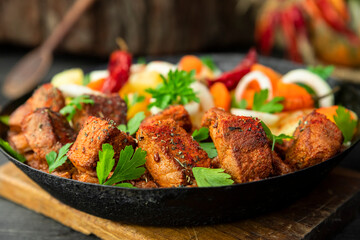 Stew with meat and vegetables in black iron dish. Traditional gourmet goulash in a rustic kitchen
