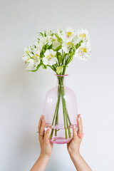 Woman holding pink glass vase with white flowers