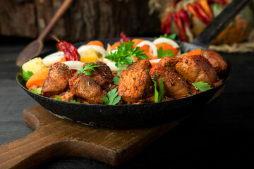 Stew with meat and vegetables in black iron dish. Traditional gourmet goulash in a rustic kitchen