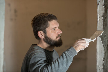 a man with a plasterer beard mounts a perforated painting corner on the corner of the doorway of...