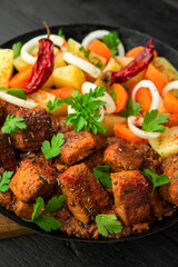 Stew with meat and vegetables in black iron dish. Traditional gourmet goulash in a rustic kitchen