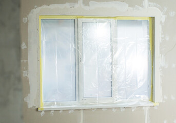 plastic window sealed with a protective film, the concept of preparation for plastering and painting works