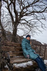 Girl on a bench under a tree on top of a mountain
