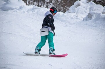 a girl on a snowboard rides down the side of the mountain