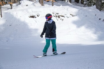 a girl on a snowboard rides down the side of the mountain