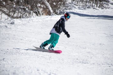 a girl on a snowboard rides down the side of the mountain