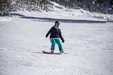 a girl on a snowboard rides down the side of the mountain