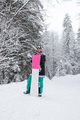 Girl with a snowboard in the forest in the mountains and the snowfall