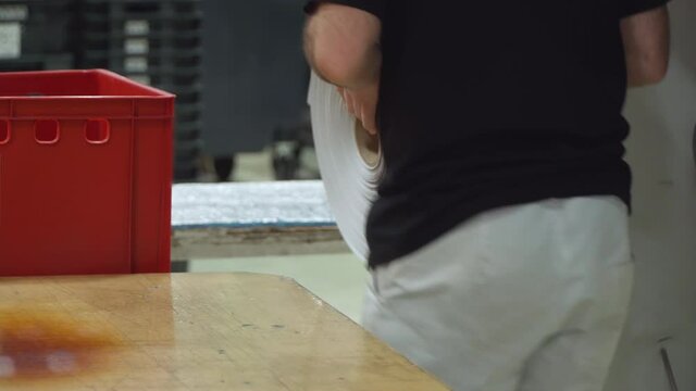 printing a photo in a printing house. A roll of printed images in a book factory. A factory employee picks up the reel with the ordered photos