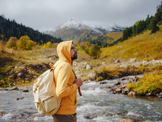 Man hikes mountains with travel backpack. Wandering lifestyle, adventure concept autumn vacation outdoors, alone in wild. Travel to North Caucasus, Arkhyz, Russia, road to Dukkinsky lakes