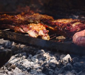 Roasted red meat over the grill in a traditional Argentinian asado. Close up detail.