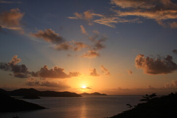 Tropical sunset over the mountains and water. Blues and oranges with clouds in sky make relaxing and calm feelings.  Taken in St. John USVI in beautiful Caribbean. 
