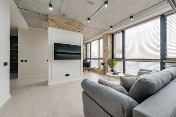 interior in a modern style and a view of the TV and part of the kitchen near the large windows with blinds