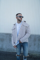 Chico joven tatuado posando con ropa urbana en la calle