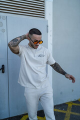 Chico joven tatuado con ropa urbana moderna posando en la calle