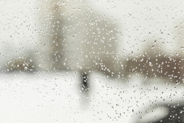 Drops of water on the glass of a car in winter, spring or autumn. The snow melts into drops on the stele of the car. View of the side window of the car from inside the car with condensate