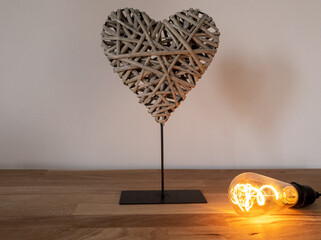 Braided decorative heart on a real wooden table and Edison lightbulb