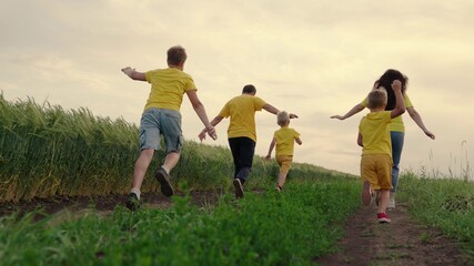 Sons, children, mom, dad run, play, rejoice, enjoy nature in summer. Family teamwork. Happy family team, running together in field, happily waving their hands. Group of people of different ages
