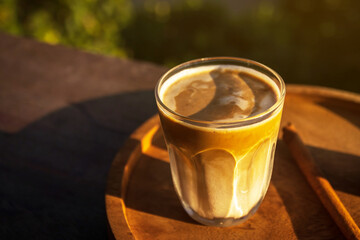 Sunrise coffee in nature. Dirty coffee on wooden table with mountain fog on shade of sunrise background. Good morning.