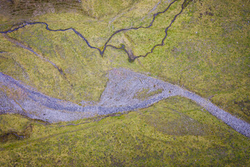 Aerial view of a dry river crossing a green meadow