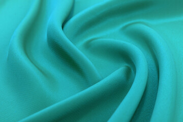 Background from a crumpled piece of green fabric with waves. Textile. Sewing material