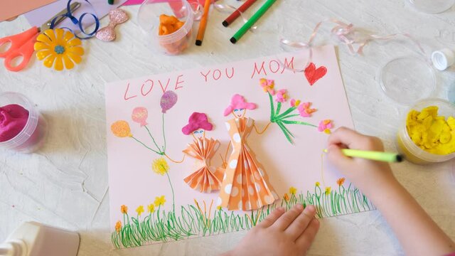 Child making homemade greeting card from paper and clay, plasticine as gift for Mothers day, Birthday or Valentines day . Arts  crafts concept.
