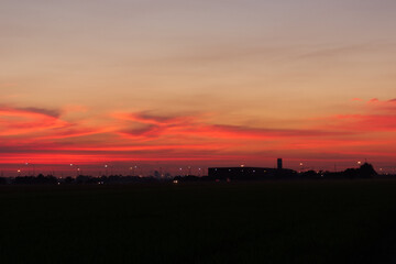 Silhouette red clouds and green fields, clouds reflecting the evening
