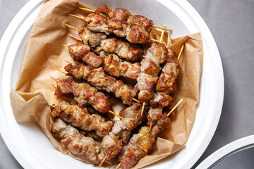 Meat kebab on a wooden skewer on a plate.