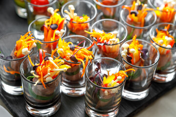 Light meat snack with Korean carrots, sprouted seeds and herbs in a glass cup.