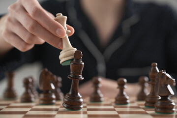 girl player performs a move with a chess piece king from a tree. Chess piece in the air, fingers are holding chess. Close-up of a chess game
