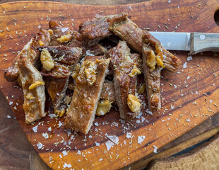 Close up of freshly cooked pork Secreto de ventresca pure iberico, iberian pig cut, with garlic, salt gems, rosemary and a knife on a wooden board