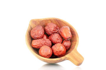 Several dried ziziphus berries with a wooden dish, close-up, isolated on white.