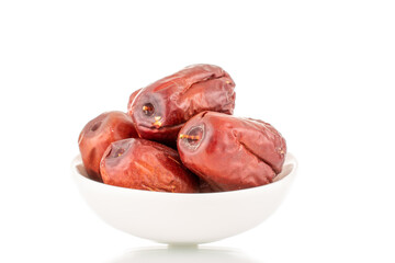 Several sweet dried ziziphus berries with a white ceramic saucer, close-up, isolated on white.