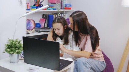A woman and her daughter are doing homework together on a laptop during the pandemic and distance learning.
