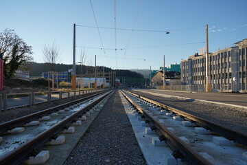 Obraz premium Civil engineering of street car line with rails on the ground. The traction cables are already installed. The line goes through industrial zone of village Urdorf.