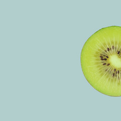 Kiwi fruit half macto shot against the pastel blue background. Healthy food minimal concept.