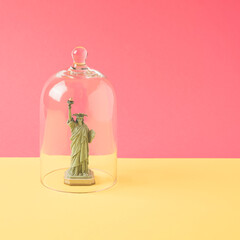 Statue of liberty figurine under the glass bell. United States isolation minimal concept.